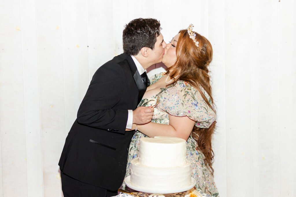 Trinh and Justin share a kiss as they cut their wedding cake at Park Winters by Sacramento Wedding Photographer