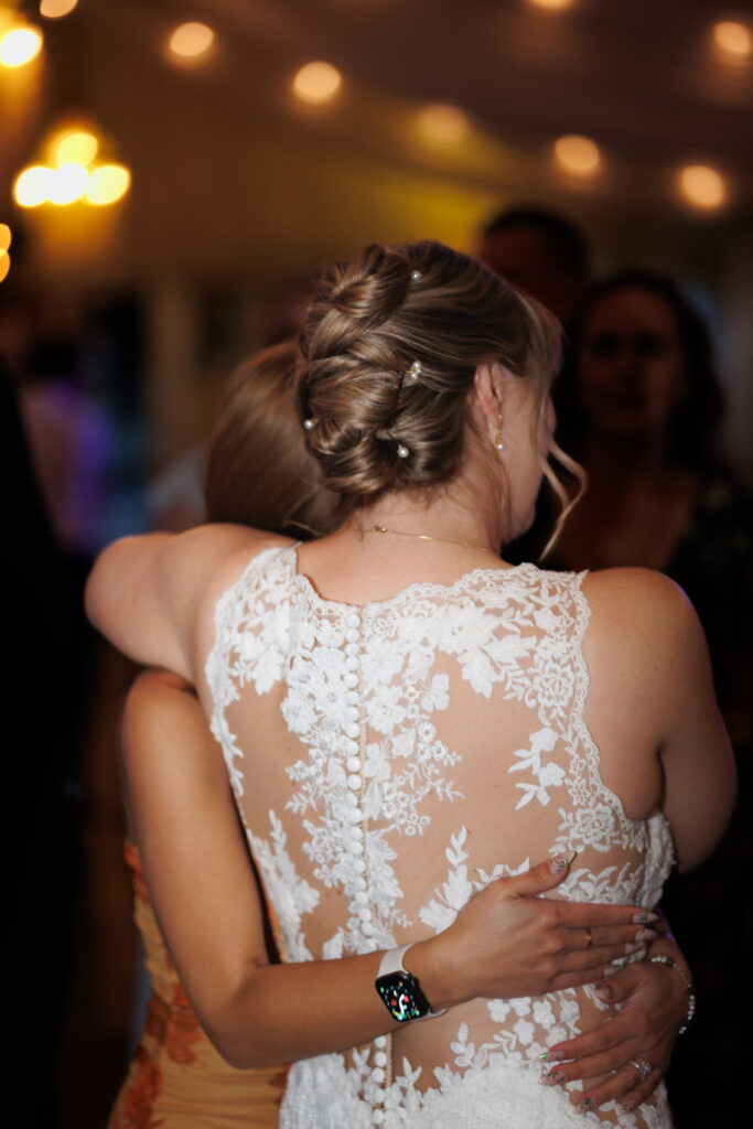 bride hugging friend at reception at jefferson street mansion captured by sacramento wedding photographer