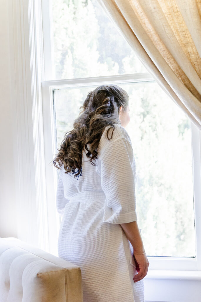 bride looks out window at venue at Park Winters in Winters, California captured by a sacramento wedding photographer