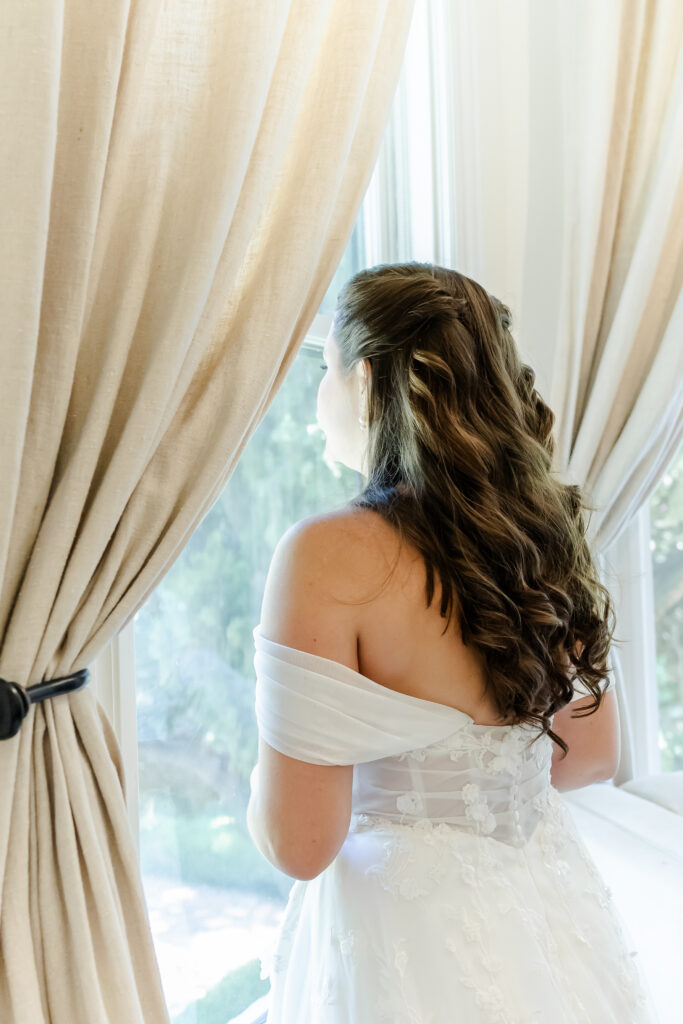 bride looks out window at Park Winters in Winters, California captured by a sacramento wedding photographer