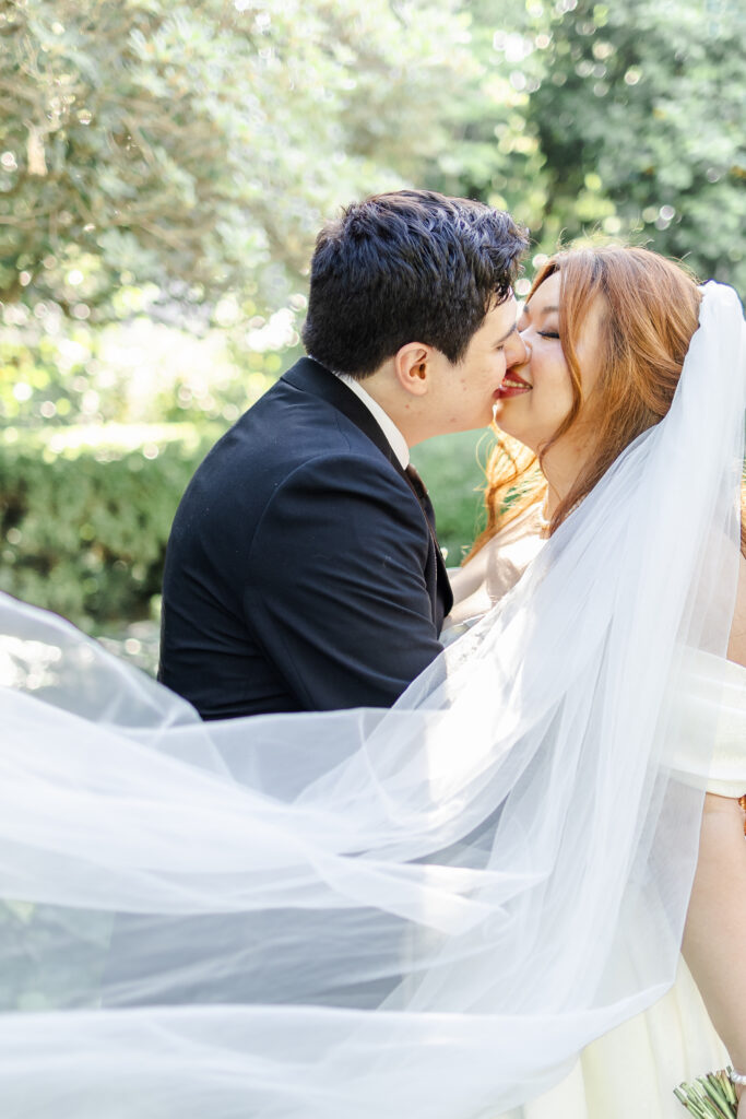 Bride and Groom enjoy a moment together with bride's veil blowing in the wind in the garden path at Park Winters Wedding captured by Sacramento Wedding Photographer
